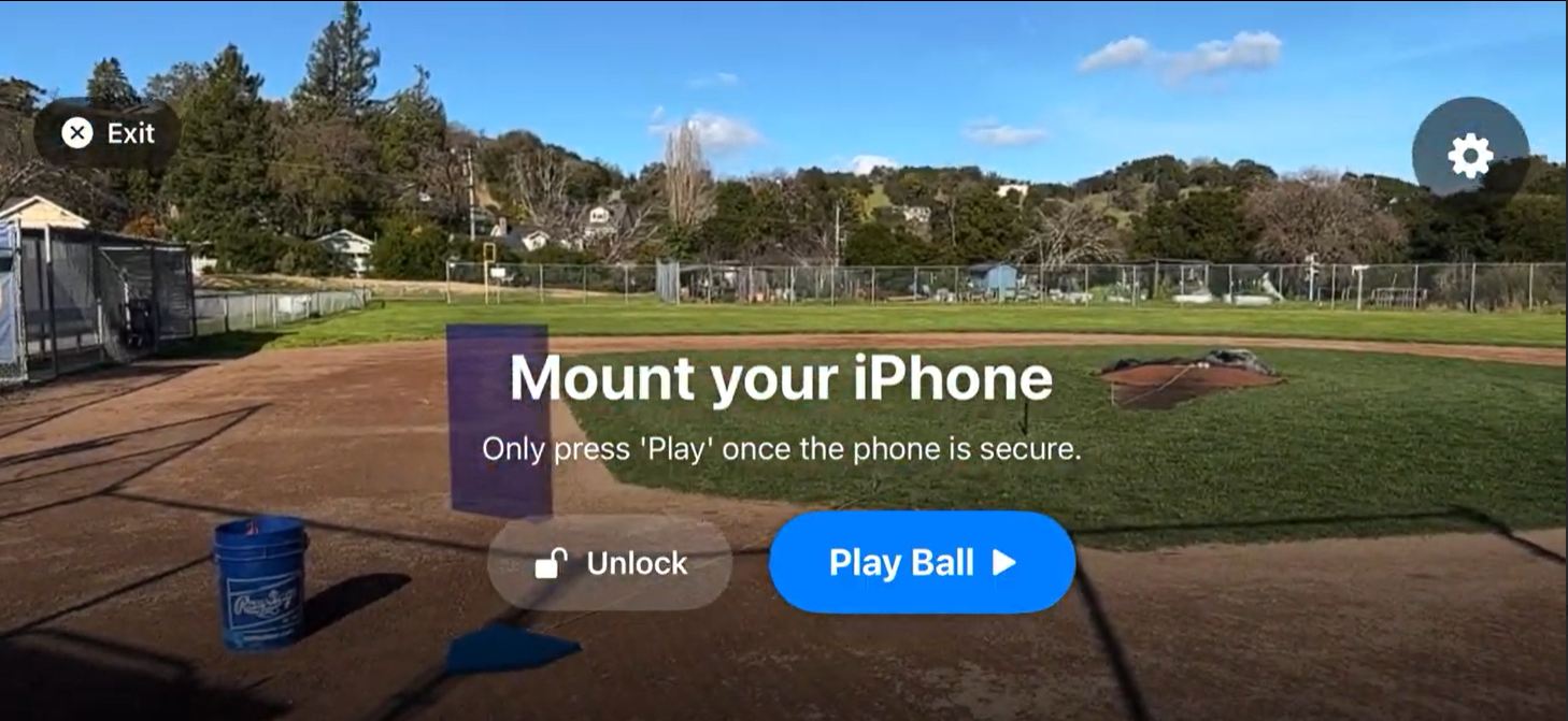 iPhone mounted on a tripod behind a chain-link backstop—the full HeyBLU hardware setup